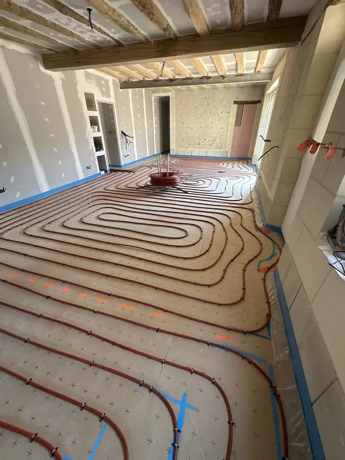 Boucles de plancher chauffant en cours de pose dans une longère à poutres apparentes en Sarthe